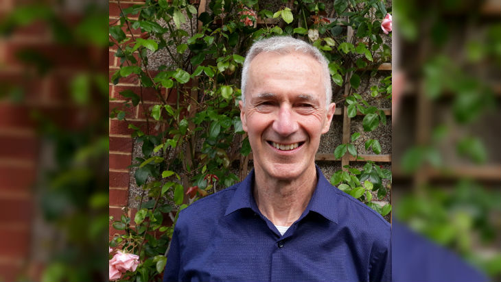 Ken Brown in front of a green-leafed bush