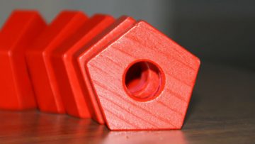 A close up of a line of red wooden pentgonal shapes.