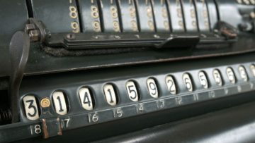 an old fashioned calculator, in faded black bakelite, showing the first ten digits of pi
