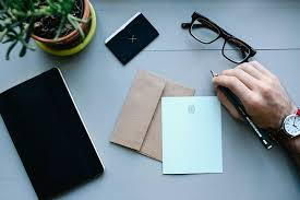 Image of desk with hand ready to write a letter.