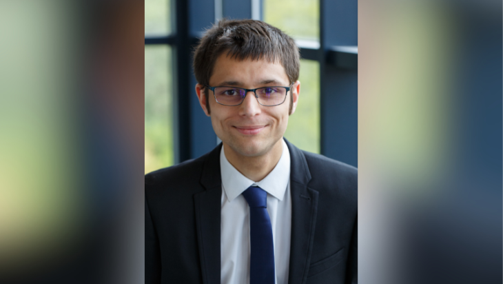 Head and shoulders image of Kieran Kalair wearing a dark suit and glasses
